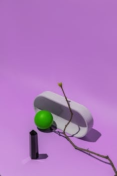 A geometric still life with a purple backdrop featuring minimalist objects.