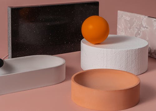 Orange Ball Lying on a White Concrete Object among Ceramic Containers and Marble Boards