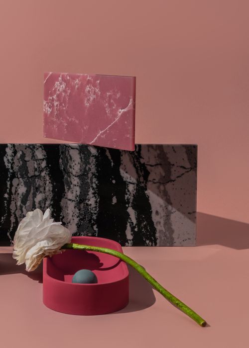 Free Minimalist still life featuring marble slabs and a white flower on a pink background. Stock Photo
