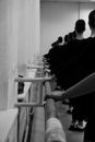 Unrecognizable ballerinas exercising against ballet barre in hall