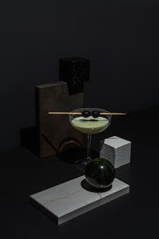 A modern minimalist composition featuring geometric shapes and a cocktail glass with olives.