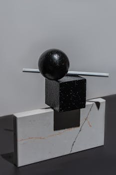 Abstract minimalist sculpture with geometric shapes and shadows on a gray surface.