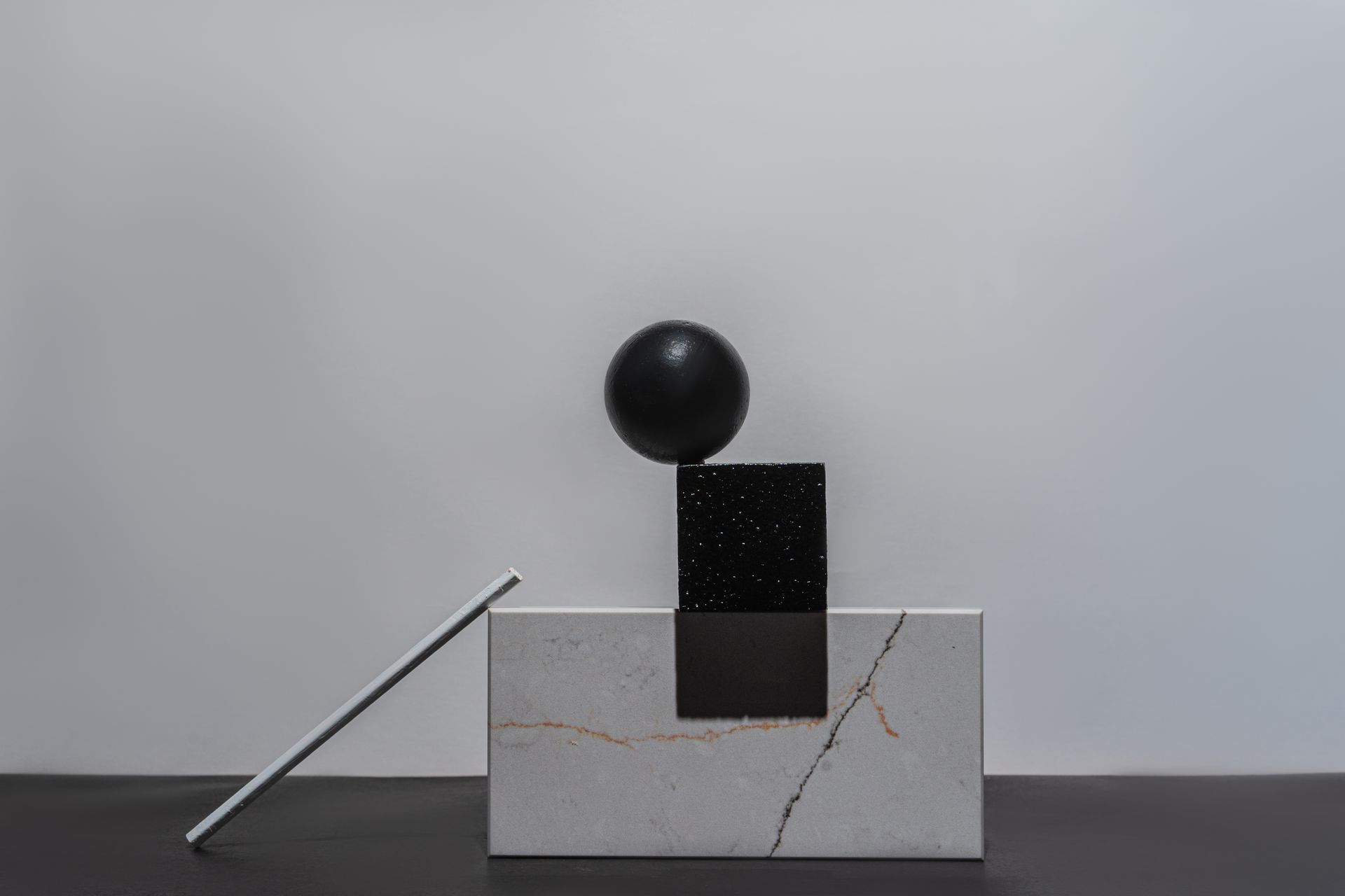 Modern still life featuring geometric shapes and a marble block in a minimalist setting.
