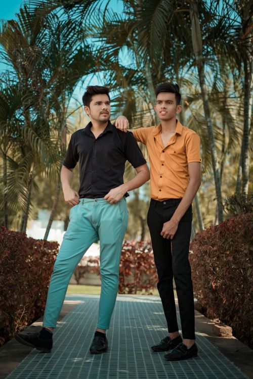 Free Two men standing confidently among palm trees on a sunny day in Dubai. Stock Photo