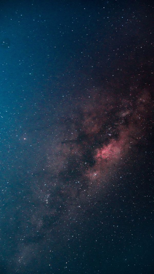 Uma impressionante imagem vertical da galáxia Via Láctea iluminando o escuro céu noturno.