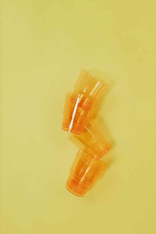 Free A minimalist image of orange plastic cups stacked on a yellow background, perfect for recycling themes. Stock Photo