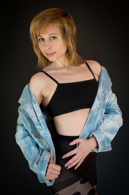 Free Confident woman with blonde hair poses in a denim jacket and crop top in studio. Stock Photo