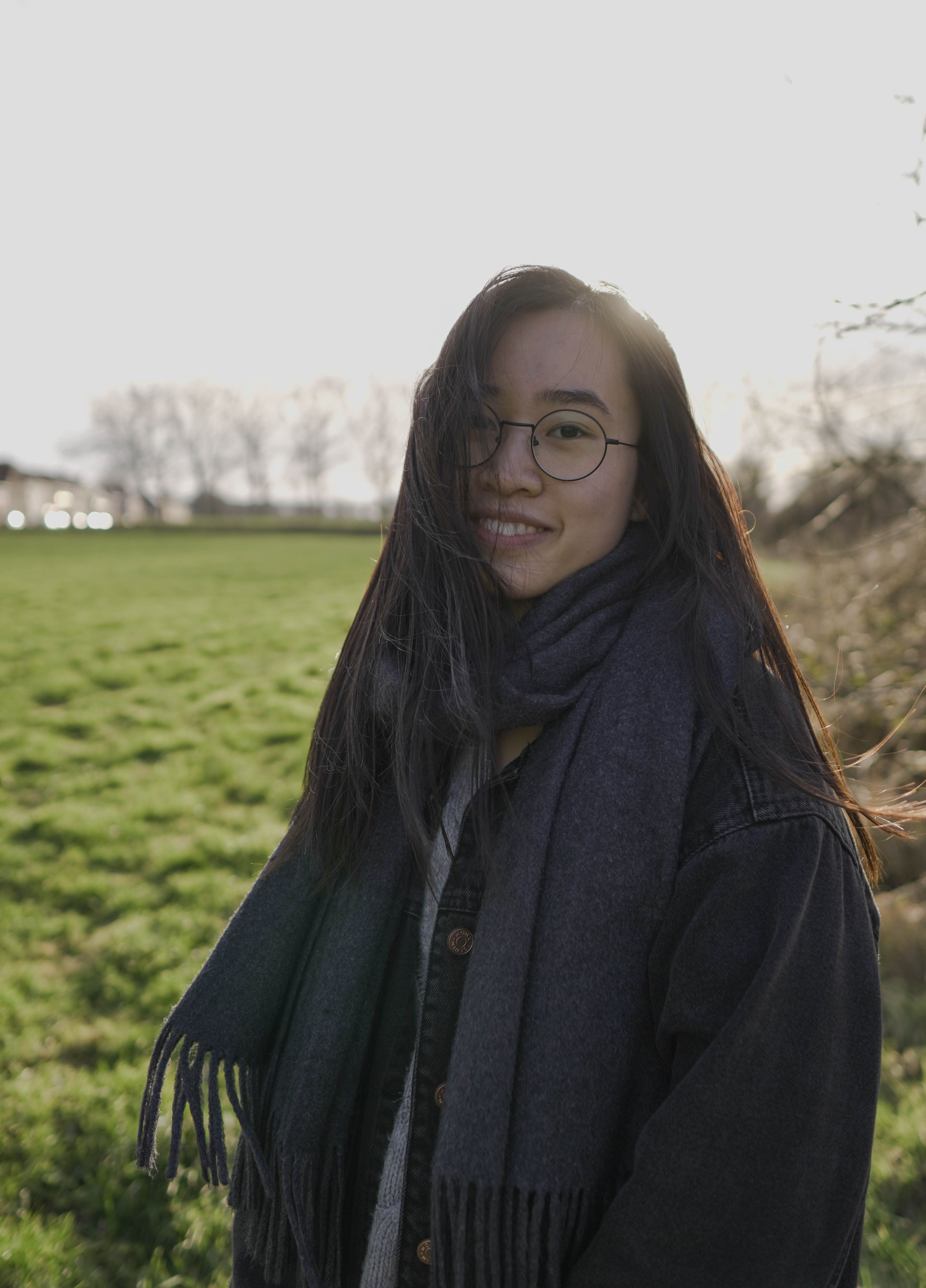 A Woman in Black Jacket Standing on Green Grass Field · Free Stock Photo