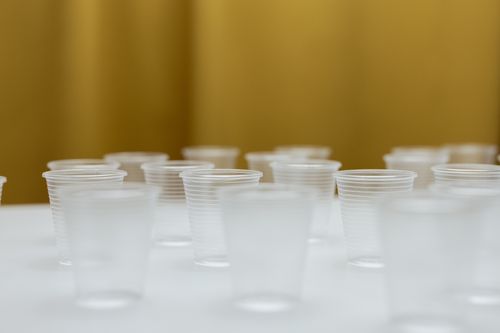 Free A collection of clear plastic cups arranged on a white table with a blurred background. Stock Photo