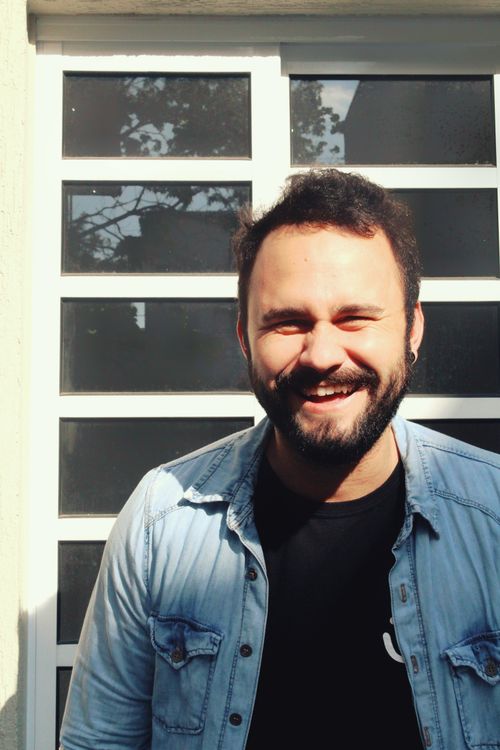 Free A happy man in a denim jacket and black shirt smiling brightly outdoors. Stock Photo