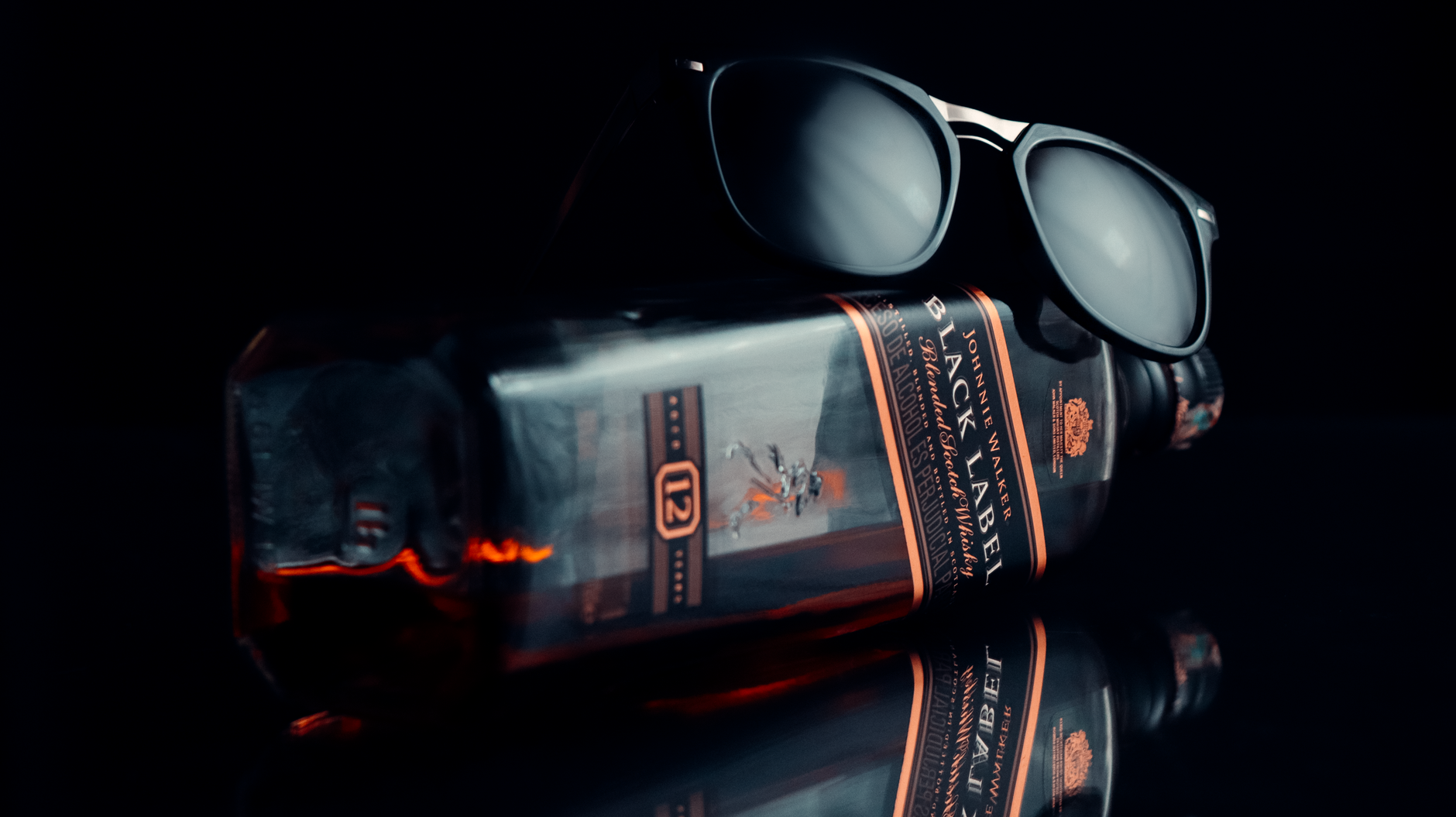 A glass of Scotch whiskey with a warm golden hue surrounded by bottles