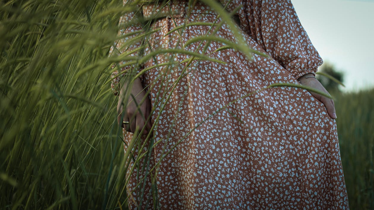Crop woman in dress standing in grassy field · Free Stock Photo