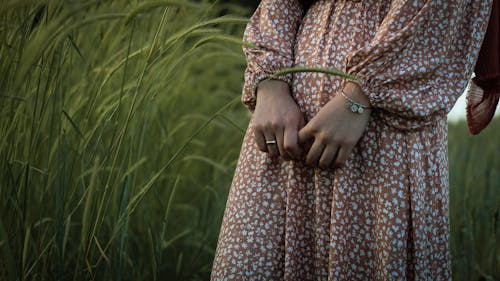 Crop woman in dress standing in field