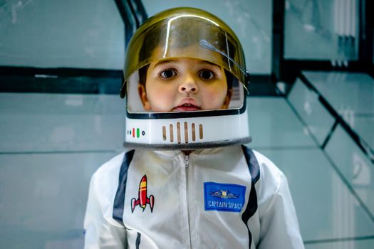 Cute boy with brown eyes wearing captain space costume and helmet and looking away, free online jigsaw puzzle on JigsawPuzzlesFreeOnline.org