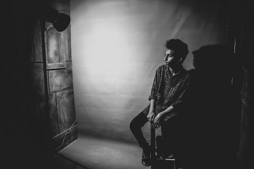 Grayscale Photo of a Man Sitting on a Chair