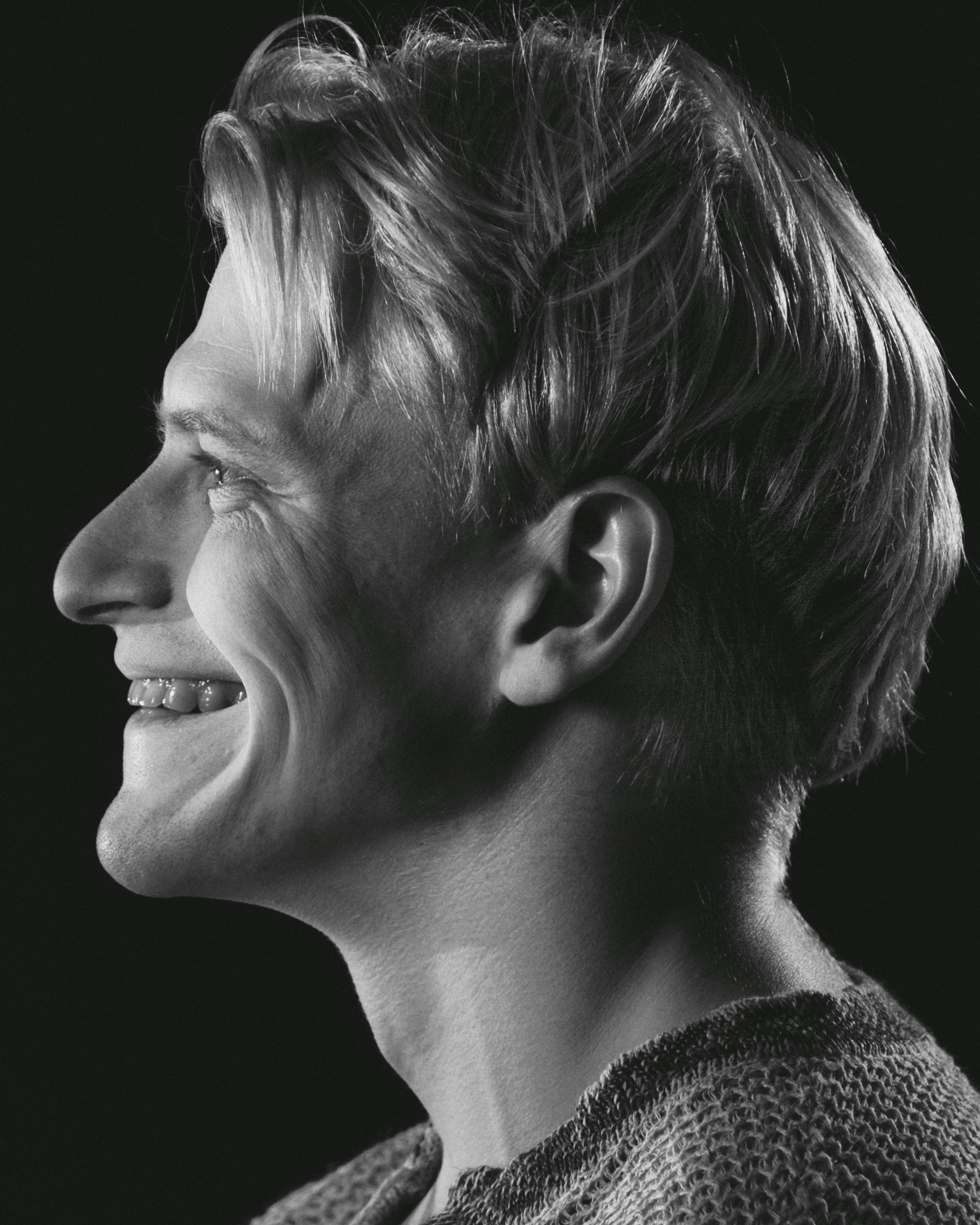 Black and white side view portrait of a smiling man. Captures a candid, happy moment.