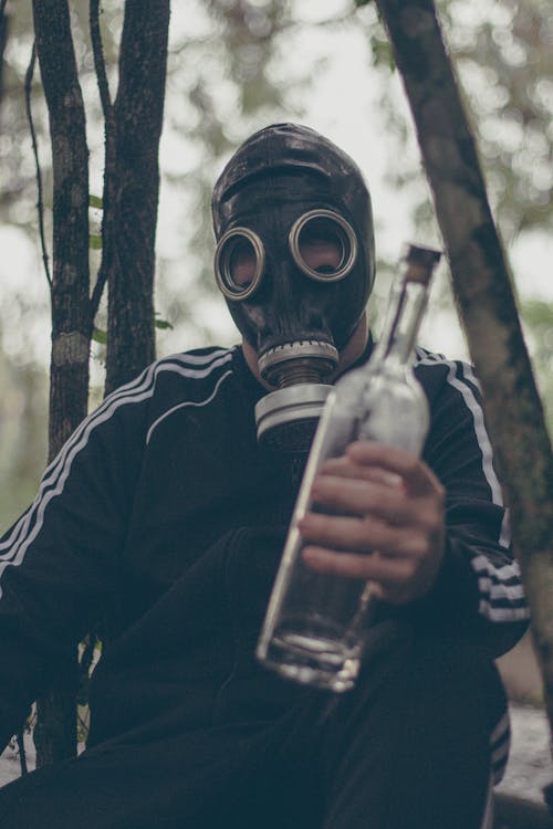 A Person Wearing a Gas Mask Holding a Bottle