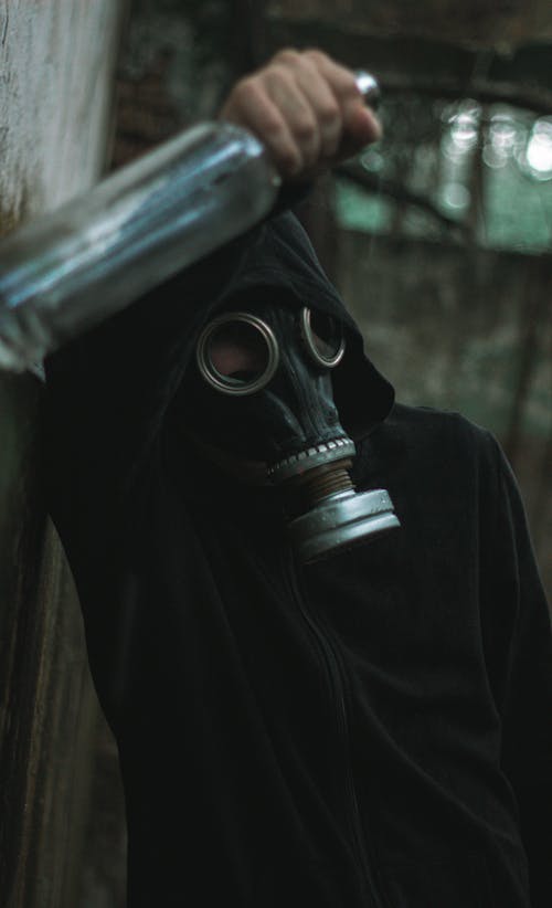 Person in Gas Mask Holding Bottle