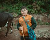 Boy in Orange Jacket Standing Beside Black Horse