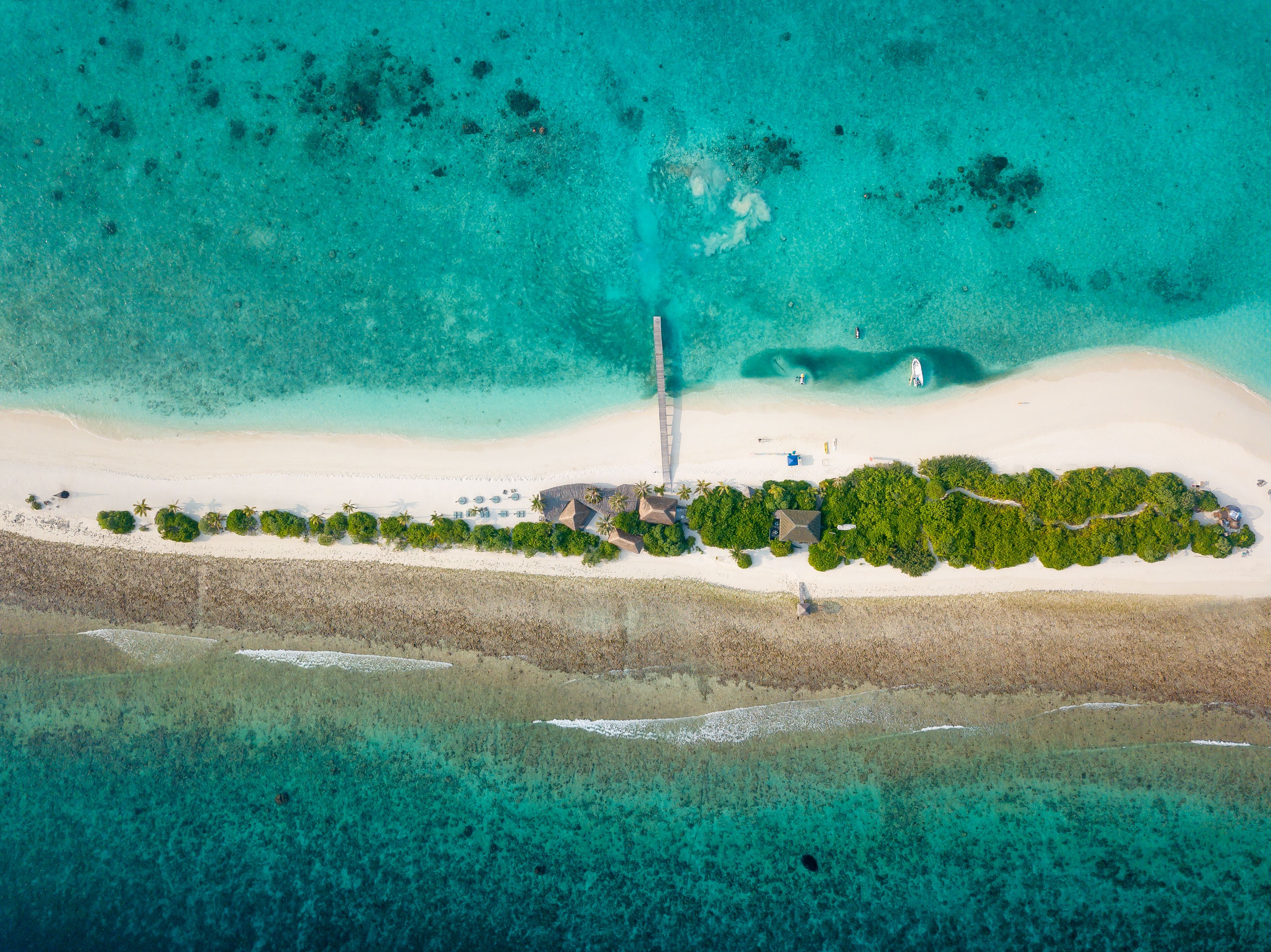 Aerial view of sandy coastline of tropical island surrounded by clean turquoise ocean waters in bright daylight