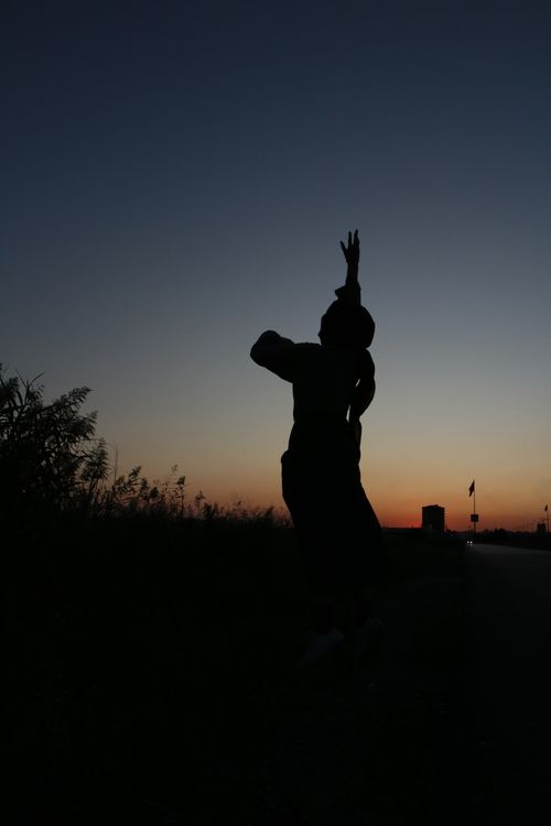 Free Silhouette of unrecognizable lady standing with raised arms in countryside on background of night cloudless sky Stock Photo