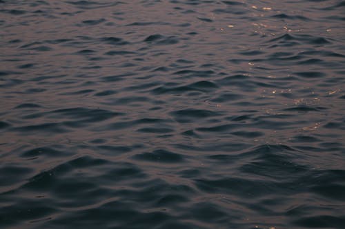 From above of dark blue rippling sea with ripples on surface in evening