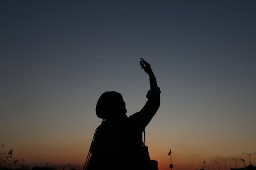 Person silhouette with raised arm at night