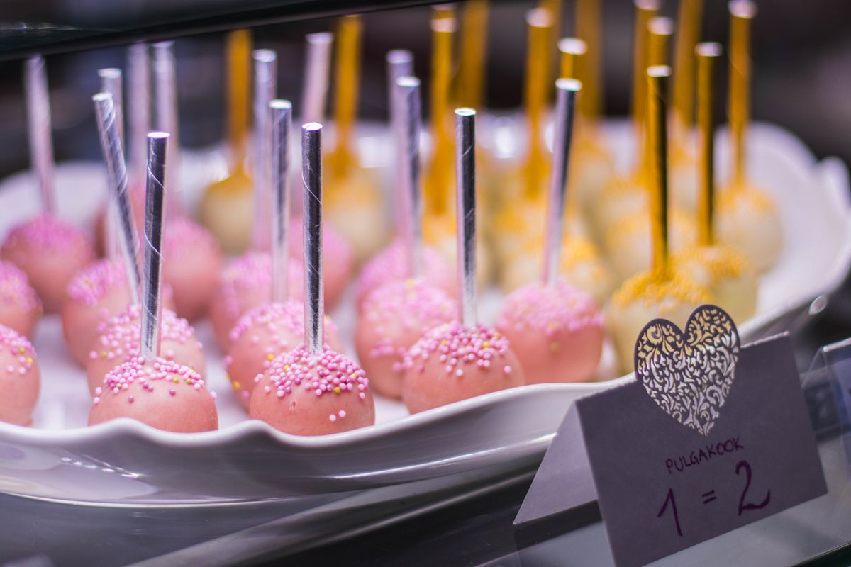 Pink and yellow cake pops on a white plate