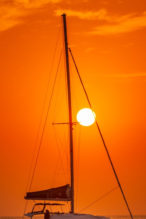 Picturesque view of yacht with high mast floating alone in evening time in bright sunset light