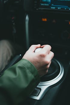Hand gripping gearshift in a car interior, showcasing driving concentration and precision.