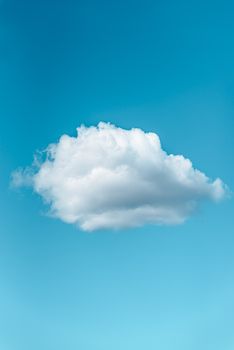 Low angle of lonely white fluffy cloud floating in blue sky in sunny day