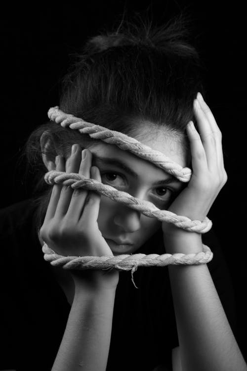 Grayscale Photo of a Woman Covering Her Face with Rope