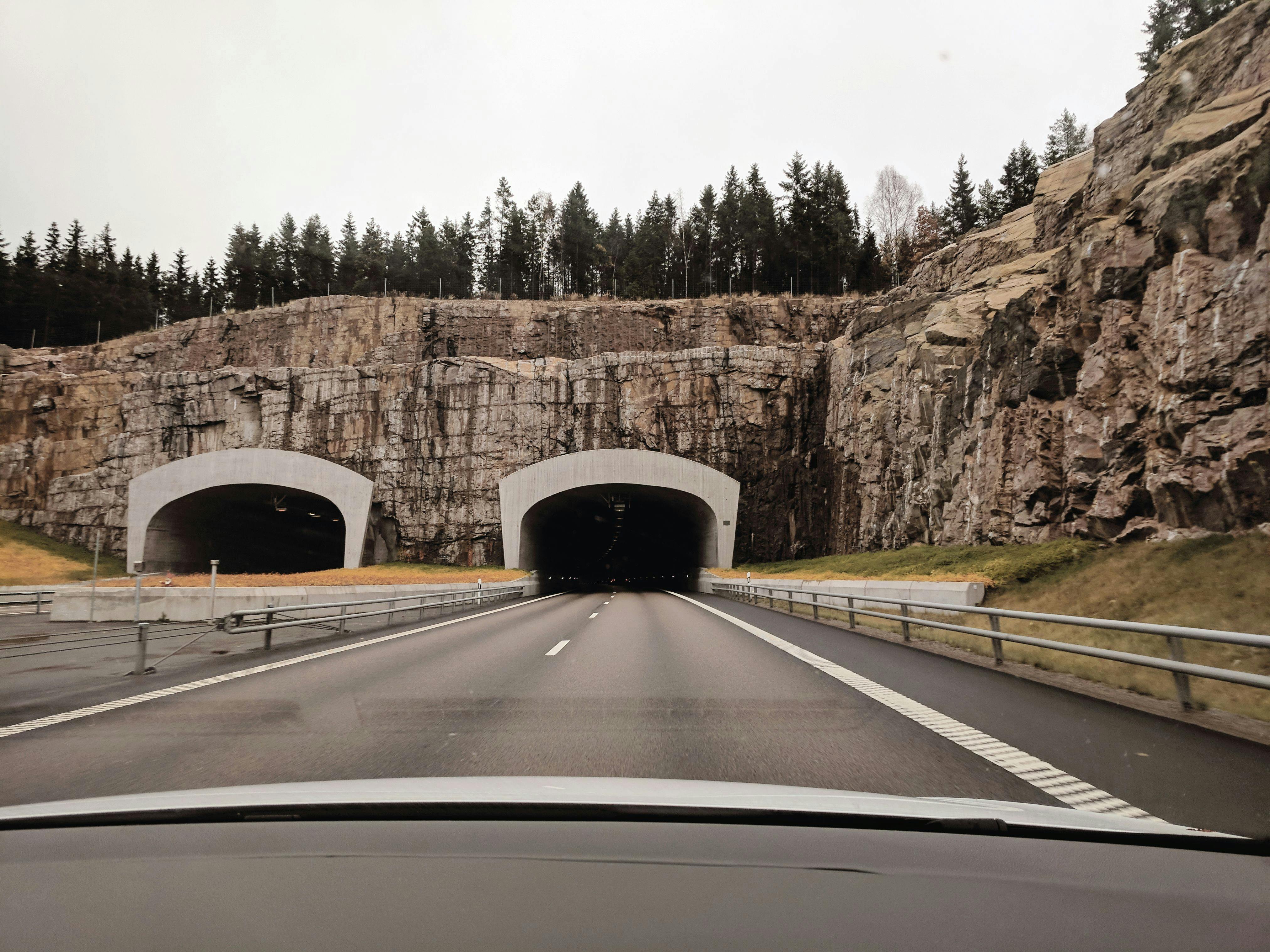 photo of two highway tunnels in cliff under cloudy sky