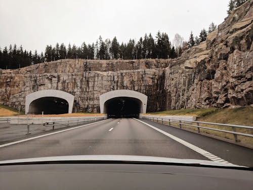 Photo of Two Highway Tunnels in Cliff Under Cloudy Sky