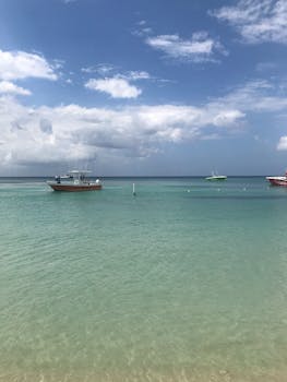 Serene ocean view with boats and blue sky, perfect for peaceful settings.