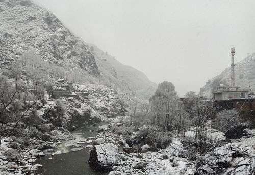 Free Breathtaking snowy landscape of Mandi with a serene river and rugged mountains. Stock Photo