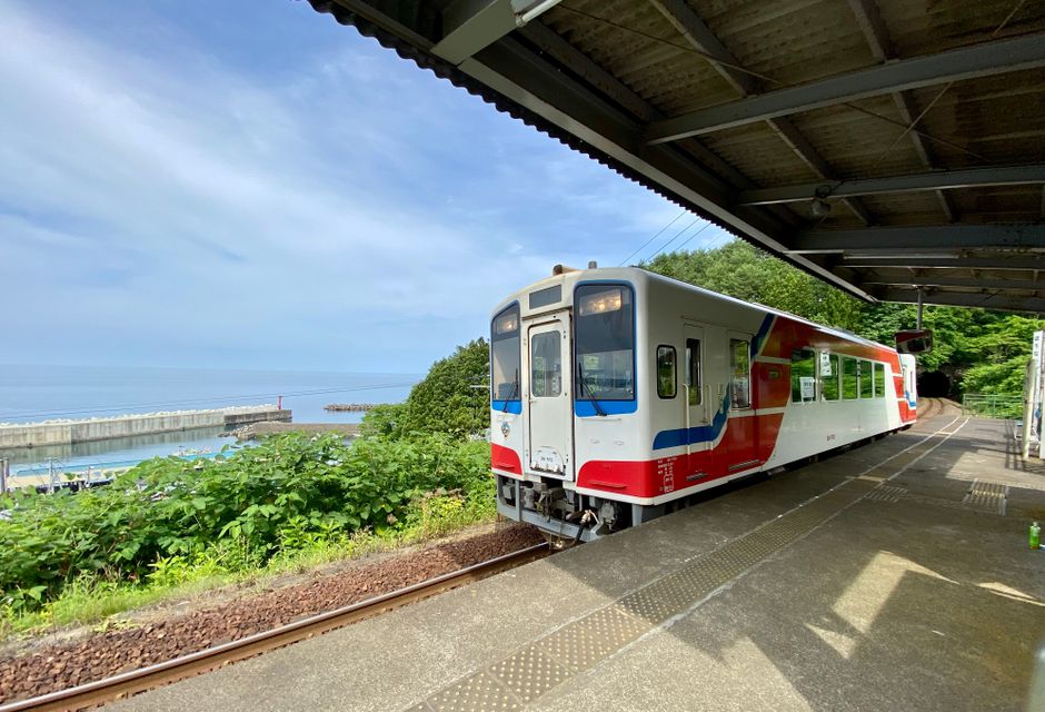 岩手県の普代駅でのカラフルな電車と海岸の景色。