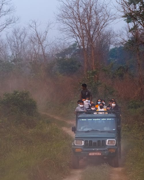 People Riding on Pickup Truck on Dirt Road