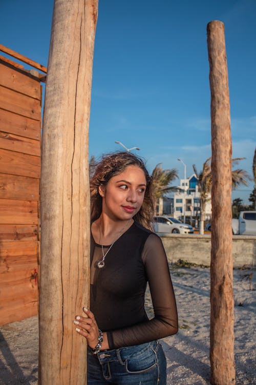 A Pretty Woman in Black Top Holding a Wooden Post