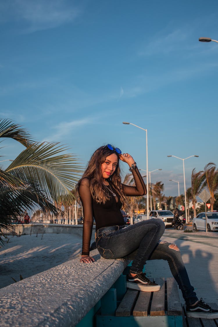 A Pretty Woman In Black Top Sitting On A Concrete Bench