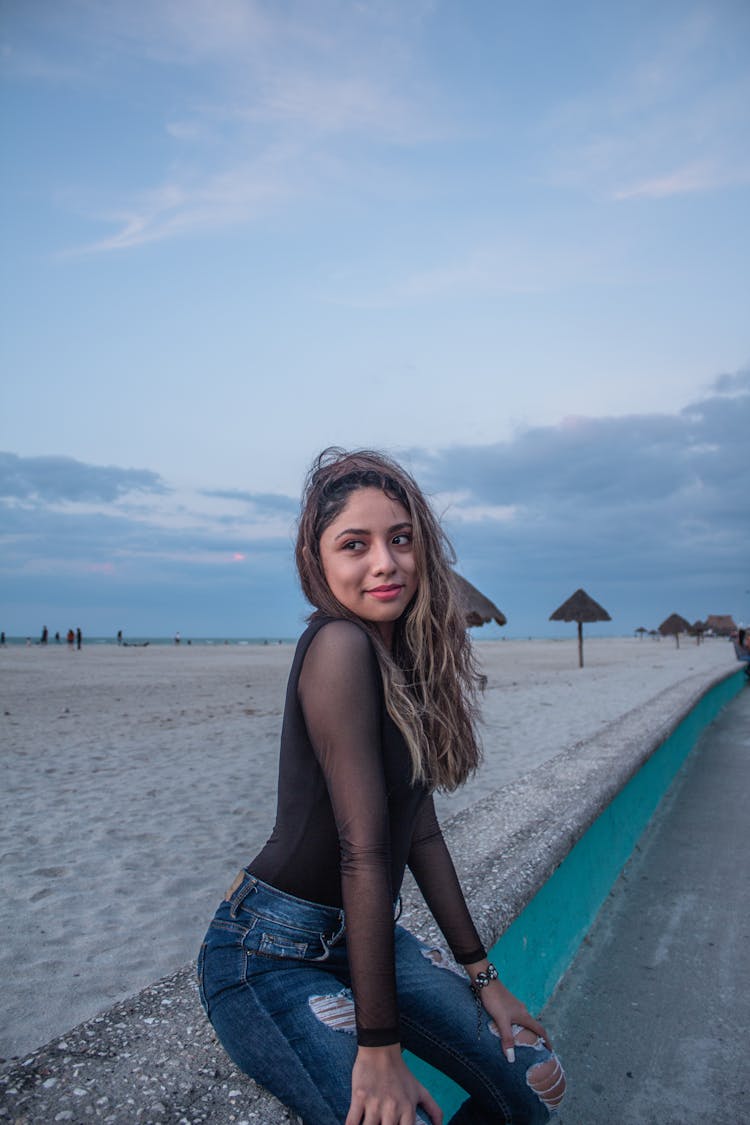 A Pretty Woman In Black Top Sitting On A Concrete Bench