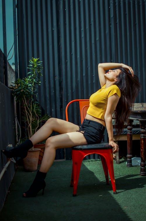 Side View of a Model Sitting on a Chair while Touching Her Hair