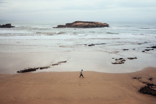 Photo of a Person Walking at the Beach