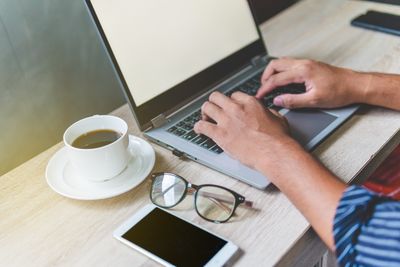 Man typing at a desk with morning coffee — photo by Kritsada Seekham on Pexels