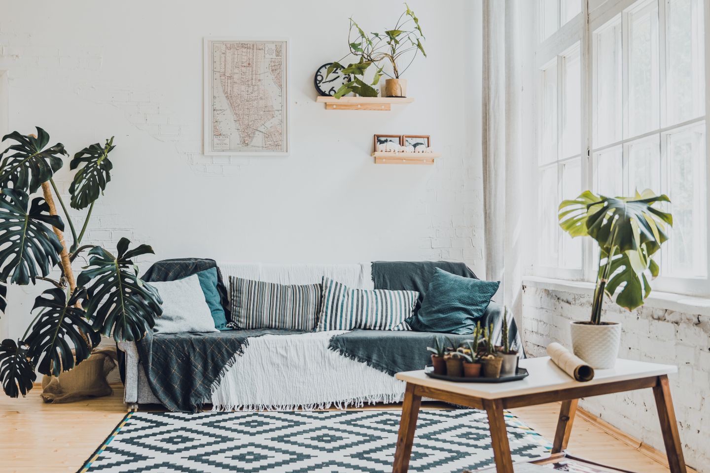 Sunlit living room with a draped sofa, monstera plants and a low wooden table — Stanislav Kondratiev on Pexels