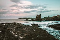 日出时分，在粉彩般的天空下，可以看到令人惊叹的海浪和崎岖的沿海悬崖