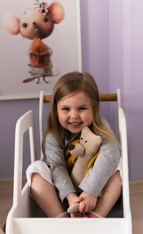 Free Close-Up Photo of a Cute Girl Smiling while Hugging Her Stuffed Toy Stock Photo