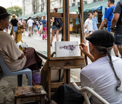 A street artist captures the lively city ambiance by painting passersby in an urban setting.
