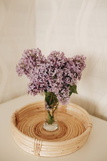 Beautiful lilac flowers in a vase on a woven tray, adding a touch of elegance to any space.