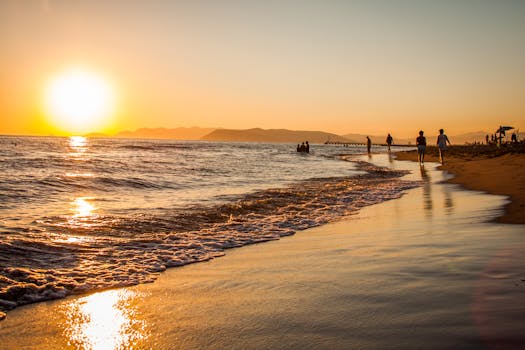 Golden sunset at a beach in Italy, with silhouettes and gentle waves.